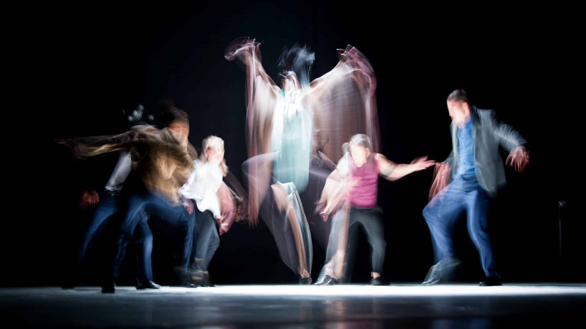 Long exposure photo of performers moving on stage