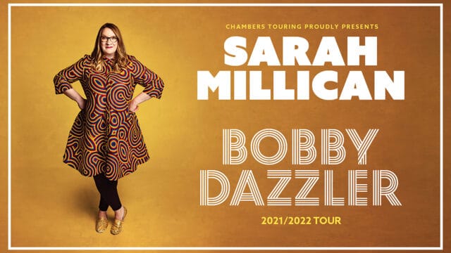Sarah Millican in a multi-coloured dress with graphic design and sparkling gold shoes against a warm golden yellow background