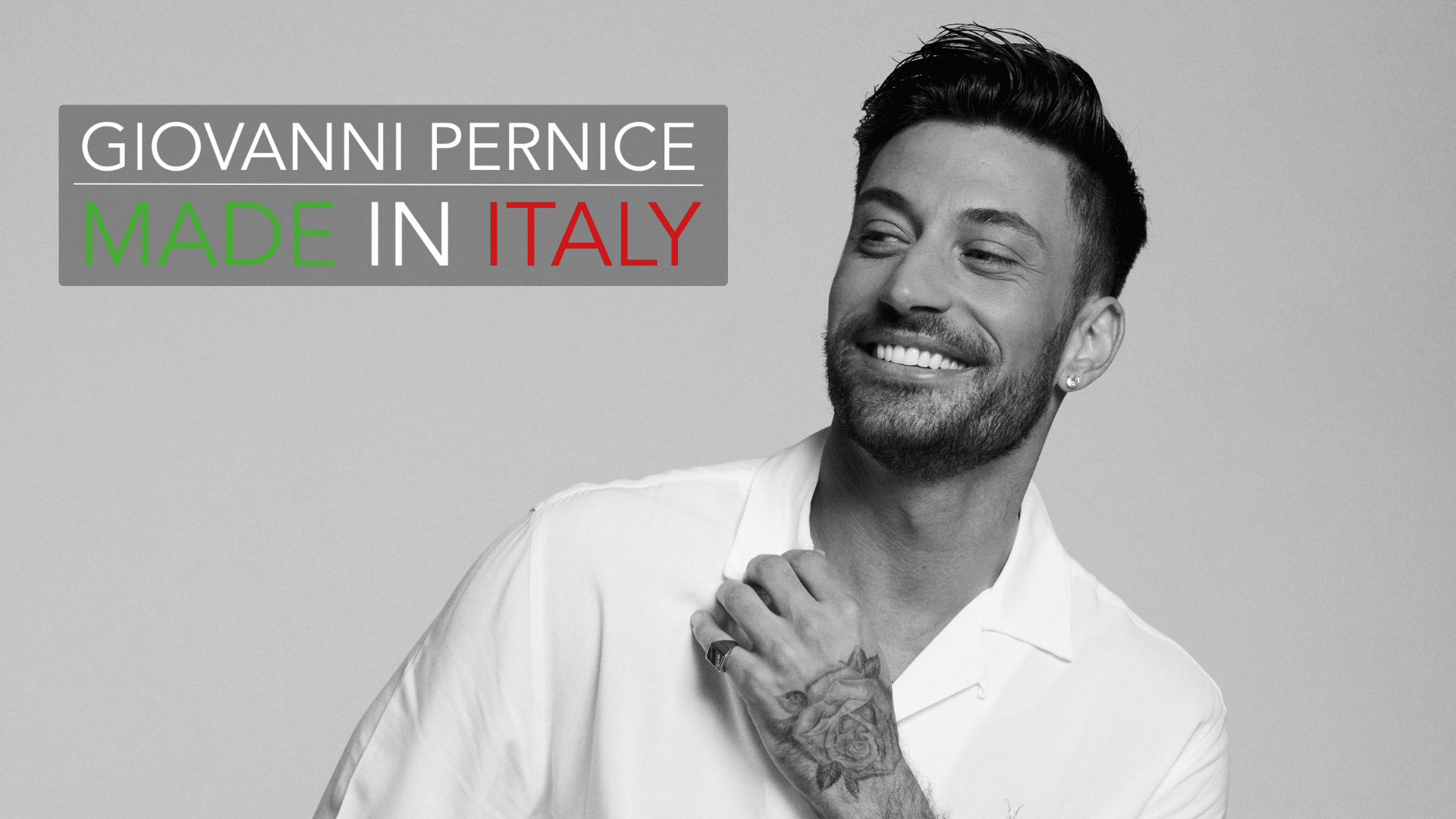 GIOVANNI PERNICE MADE IN ITALY black and white image of Giovanni smiling broadly.He's wearing a white t-shirt