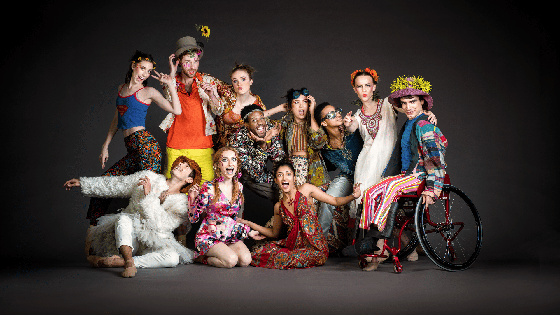 The cast of DREAM grouped together in colourful costumes and posing for the camera