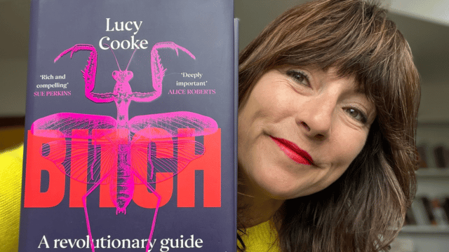 Lucy Cooke with a big smile - holding her book Bitch